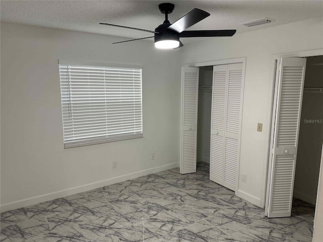 unfurnished bedroom featuring multiple closets, ceiling fan, and a textured ceiling