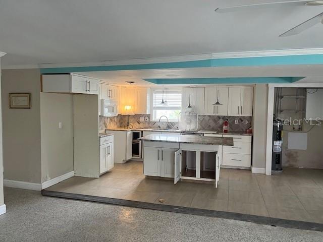 kitchen featuring a center island, electric water heater, backsplash, white cabinets, and sink