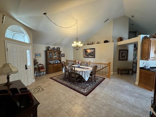 dining area with high vaulted ceiling and an inviting chandelier