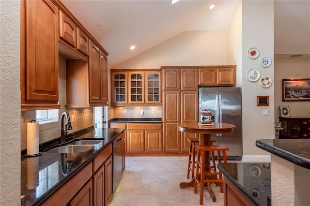 kitchen featuring appliances with stainless steel finishes, sink, decorative backsplash, and dark stone counters