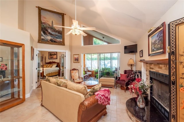 living room featuring a stone fireplace, high vaulted ceiling, and ceiling fan