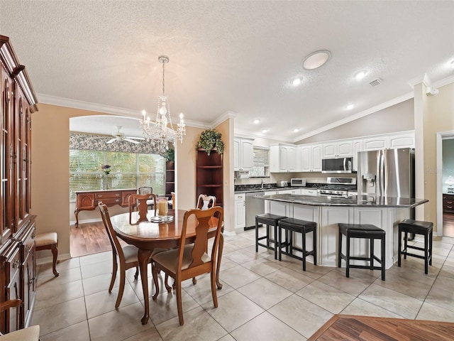 tiled dining area with ceiling fan with notable chandelier, sink, crown molding, and vaulted ceiling