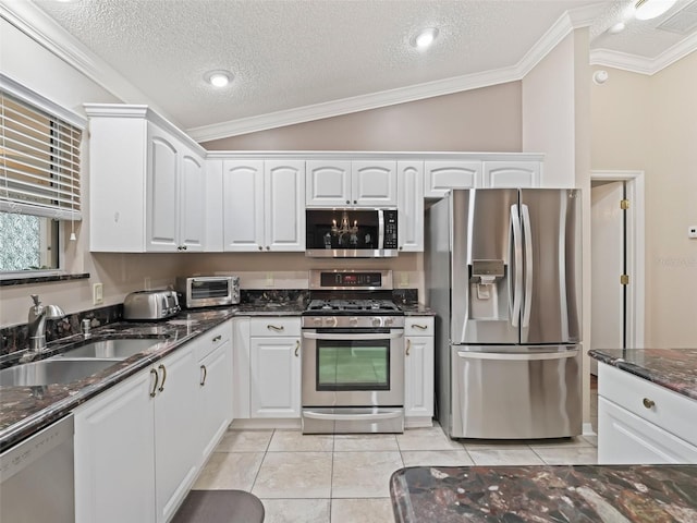 kitchen featuring vaulted ceiling, dark stone countertops, sink, stainless steel appliances, and white cabinets