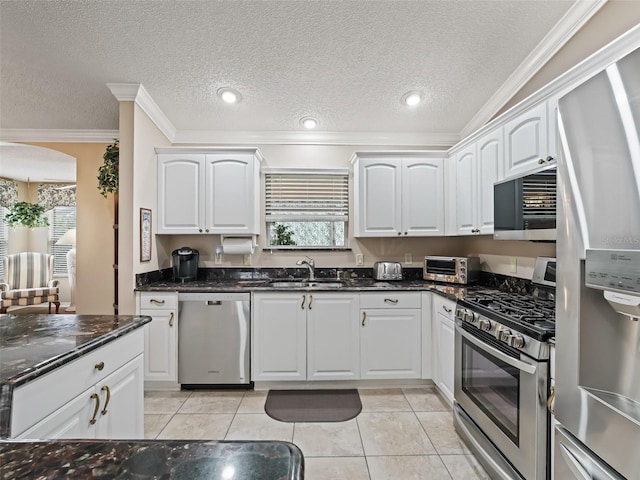 kitchen with light tile patterned floors, stainless steel appliances, white cabinets, and dark stone counters