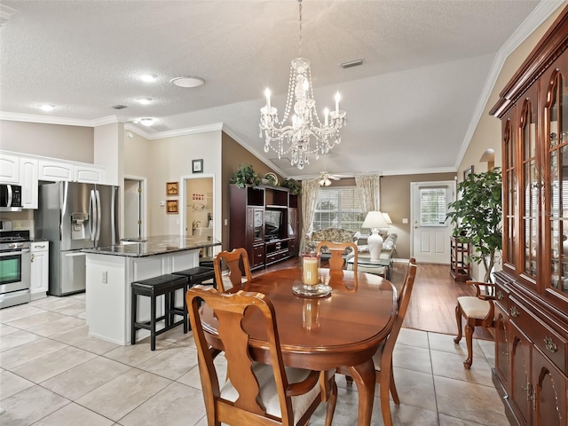 tiled dining space with ceiling fan with notable chandelier, a textured ceiling, ornamental molding, and vaulted ceiling