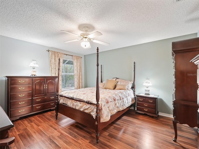 bedroom with ceiling fan, dark wood-type flooring, and a textured ceiling