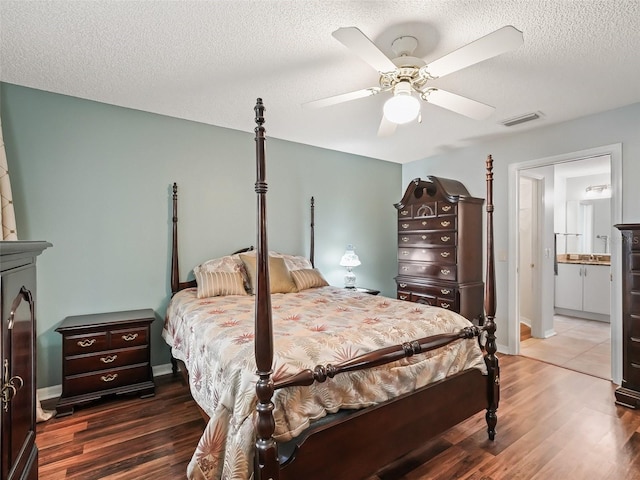 bedroom with ceiling fan, dark wood-type flooring, and a textured ceiling