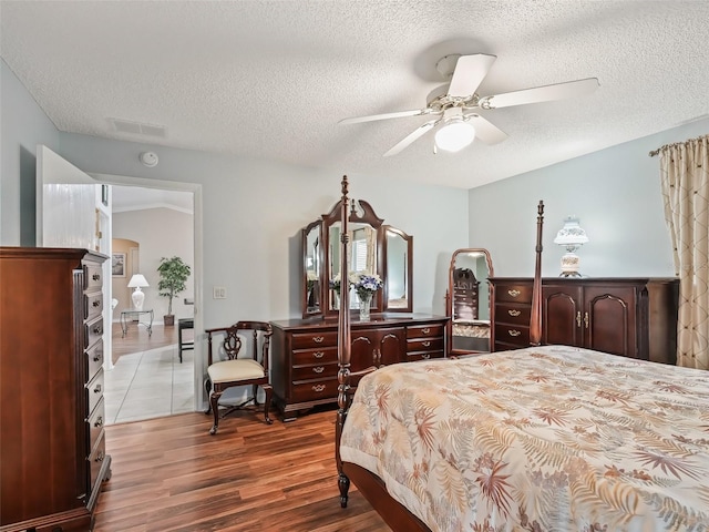 bedroom with ceiling fan, a textured ceiling, and wood-type flooring