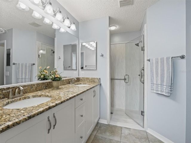 bathroom with a textured ceiling, tile patterned floors, an enclosed shower, and vanity