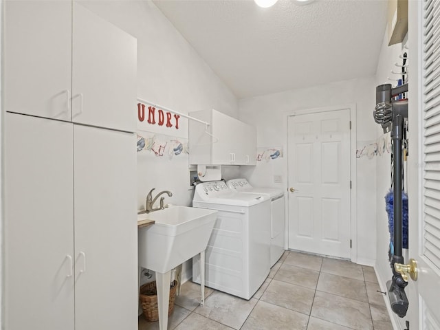 washroom with light tile patterned floors, a textured ceiling, washing machine and clothes dryer, and cabinets