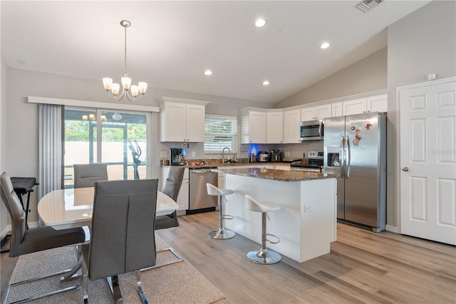 kitchen featuring appliances with stainless steel finishes, a center island, a notable chandelier, white cabinets, and decorative light fixtures