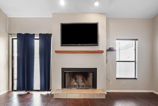 unfurnished living room with a tiled fireplace and hardwood / wood-style flooring