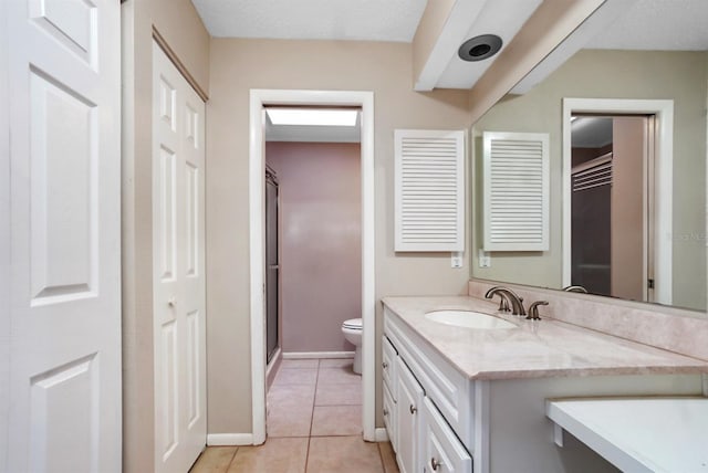 bathroom featuring tile patterned flooring, vanity, a shower with shower door, and toilet