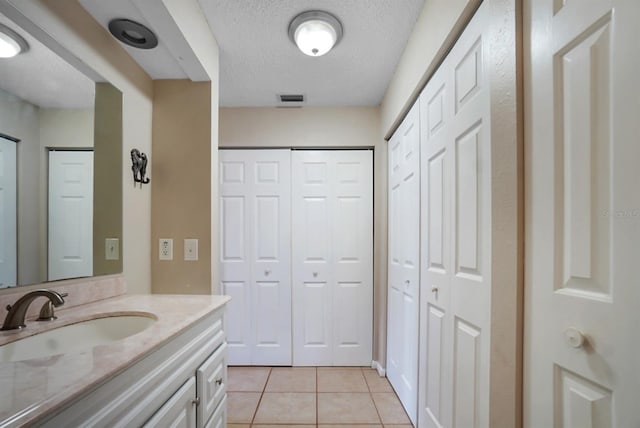 bathroom with tile patterned flooring, vanity, and a textured ceiling