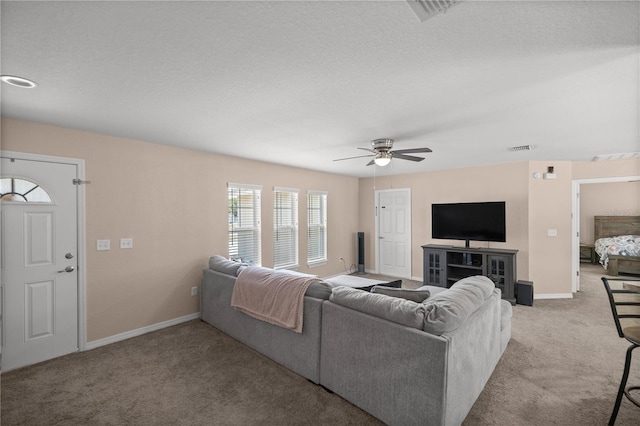 carpeted living room featuring ceiling fan and a textured ceiling