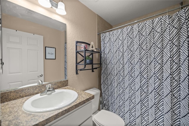 bathroom with a shower with curtain, vanity, toilet, and a textured ceiling