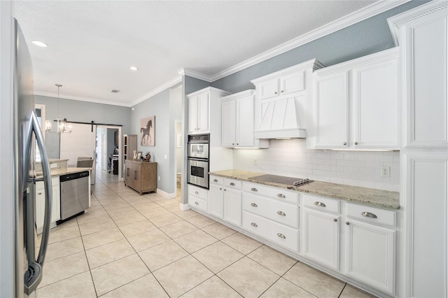 kitchen featuring white cabinets, stainless steel appliances, tasteful backsplash, premium range hood, and a barn door