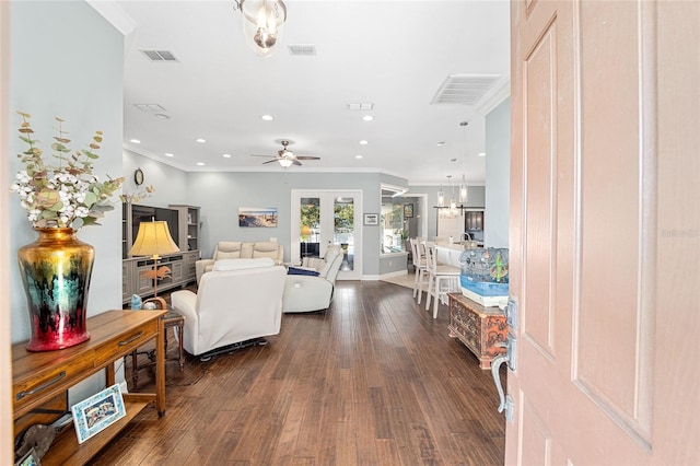 living room featuring ceiling fan with notable chandelier, ornamental molding, and dark wood-type flooring