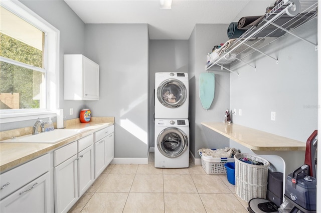 laundry area with sink, stacked washer and clothes dryer, cabinets, and light tile patterned flooring