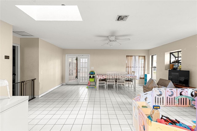 tiled living room with french doors, a skylight, plenty of natural light, and ceiling fan