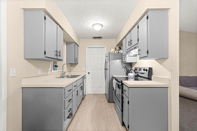 kitchen with gray cabinetry, a textured ceiling, stainless steel electric stove, sink, and light hardwood / wood-style floors