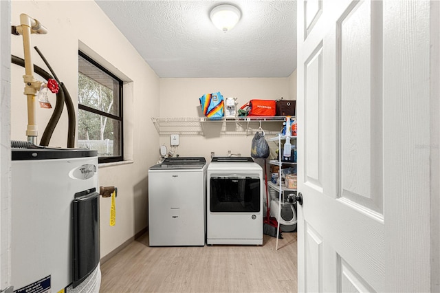 laundry area with separate washer and dryer, electric water heater, light hardwood / wood-style flooring, and a textured ceiling