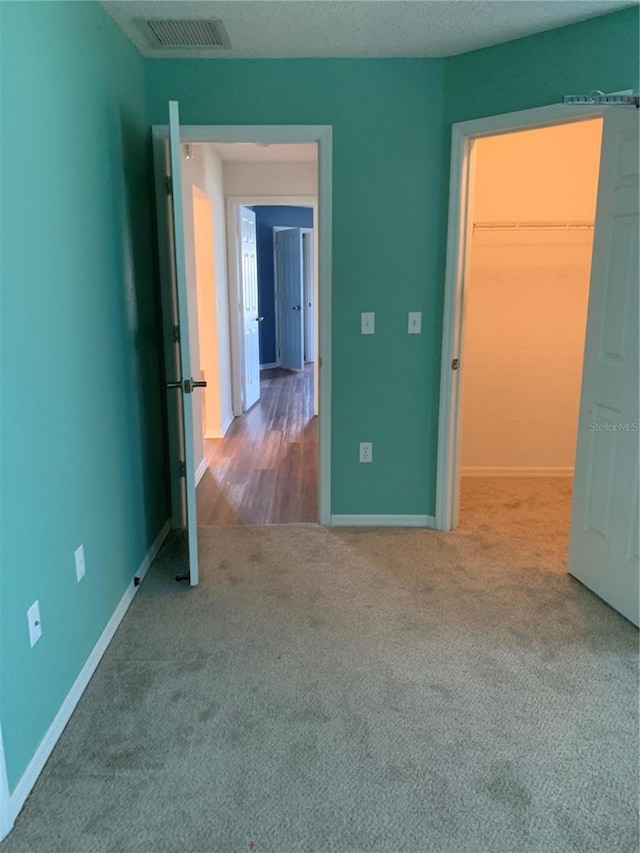 unfurnished bedroom featuring a closet, a walk in closet, and carpet flooring