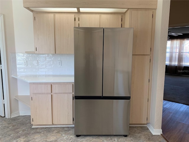 kitchen featuring light brown cabinetry, stainless steel fridge, and tasteful backsplash