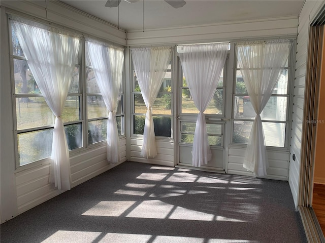 unfurnished sunroom featuring ceiling fan and plenty of natural light