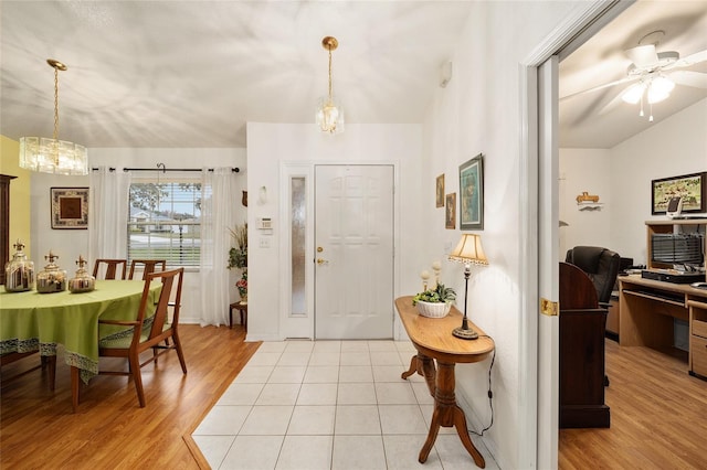 foyer with ceiling fan with notable chandelier and light wood-type flooring