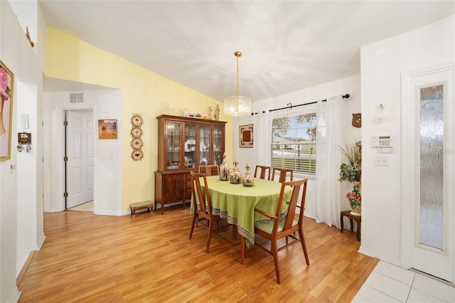 dining room featuring vaulted ceiling, an inviting chandelier, and light hardwood / wood-style floors