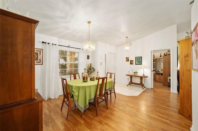 dining space with light hardwood / wood-style flooring and a chandelier