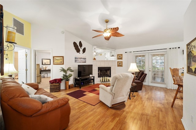 living room featuring a fireplace, light wood-type flooring, french doors, and ceiling fan