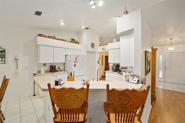 kitchen with white appliances, kitchen peninsula, sink, white cabinetry, and lofted ceiling