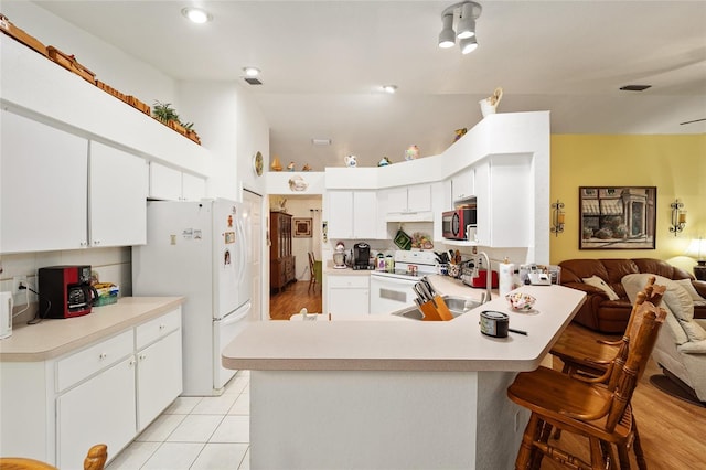 kitchen featuring white appliances, kitchen peninsula, white cabinets, light tile patterned flooring, and sink