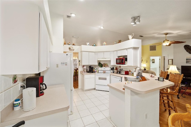 kitchen with white appliances, kitchen peninsula, light tile patterned floors, white cabinets, and sink