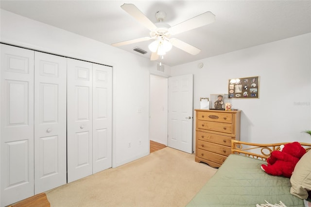 bedroom with ceiling fan, light colored carpet, and a closet