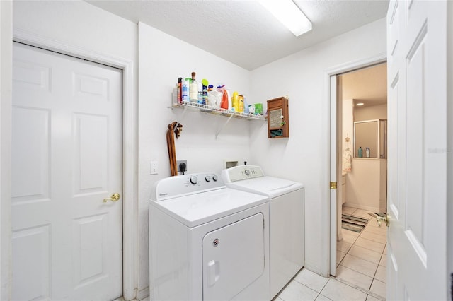 laundry area with a textured ceiling, light tile patterned floors, and washer and clothes dryer