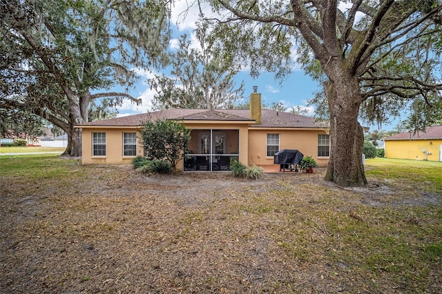 back of property featuring a lawn and a sunroom