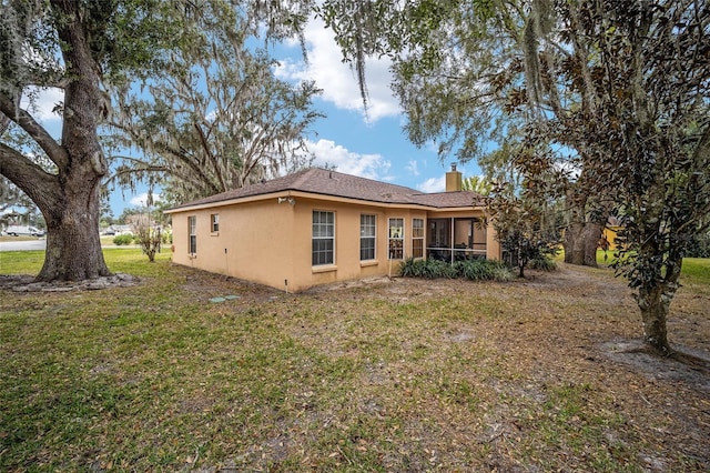 back of house with a lawn and a sunroom