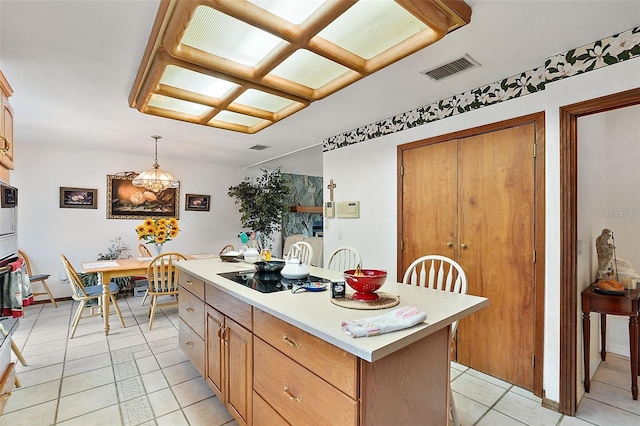 kitchen featuring black electric cooktop, a center island, light tile patterned floors, and decorative light fixtures