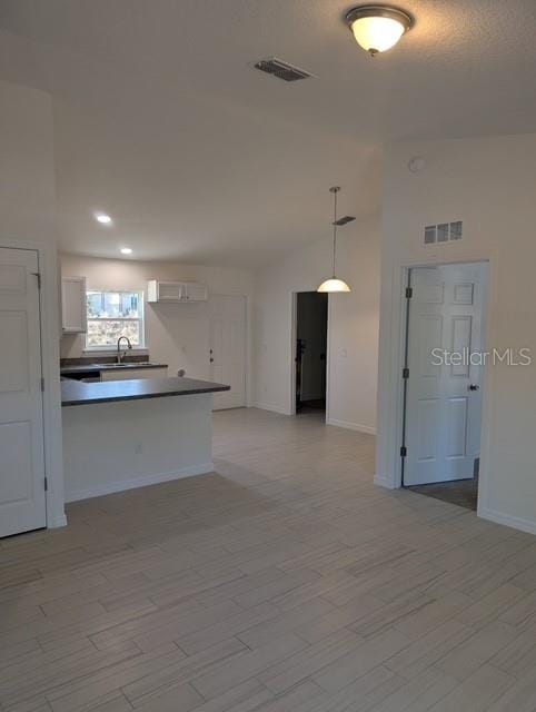 kitchen with sink, kitchen peninsula, pendant lighting, light hardwood / wood-style floors, and white cabinets