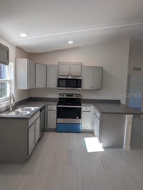 kitchen with gray cabinets, sink, stainless steel appliances, and vaulted ceiling