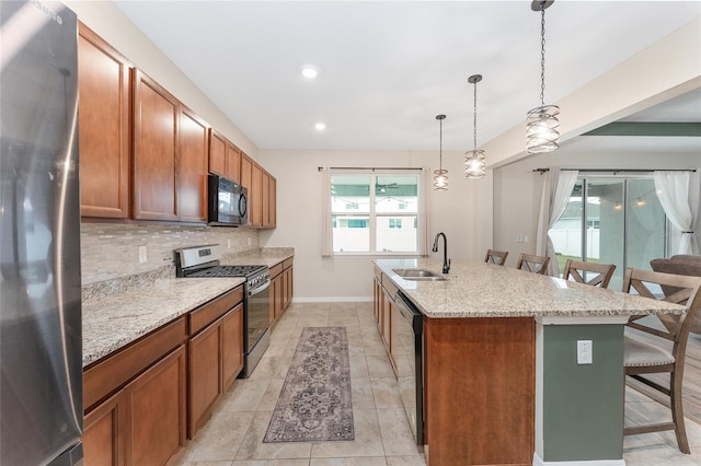 kitchen featuring backsplash, a breakfast bar, stainless steel appliances, a kitchen island with sink, and sink