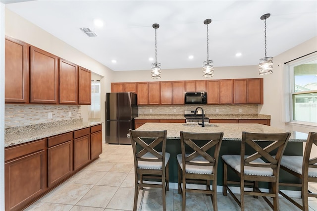 kitchen with light stone countertops, pendant lighting, a breakfast bar, and stainless steel appliances