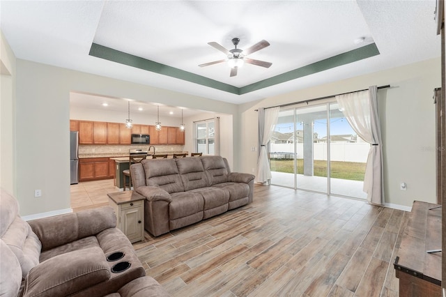 living room with ceiling fan and a raised ceiling