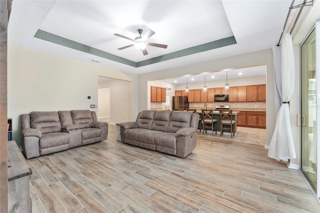 living room with ceiling fan and a tray ceiling