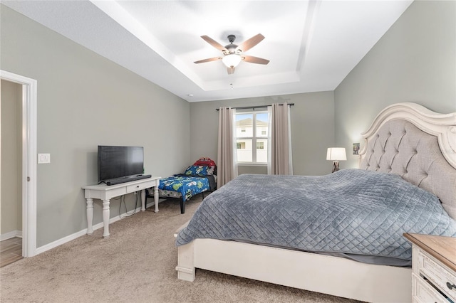 bedroom featuring ceiling fan, a raised ceiling, and light carpet