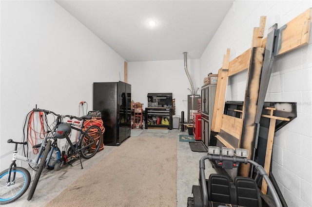 interior space with gas water heater and black refrigerator with ice dispenser