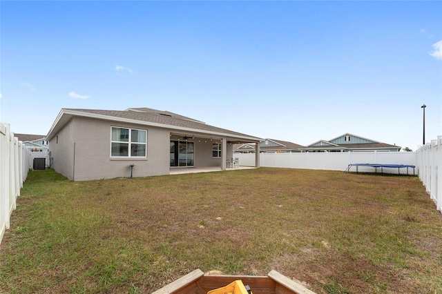 rear view of property featuring a lawn, cooling unit, and a patio